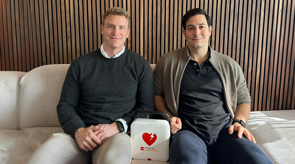 Jimmy Eriksson, CEO, and Alexander Albedj, Head of M&A sits on a sofa and in between them is a defibrillator case.
